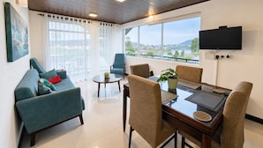 A modern living room with a sofa, chairs, a coffee table, and a TV mounted on the wall. - The Lakeside Stay (Nuwara Eliya)