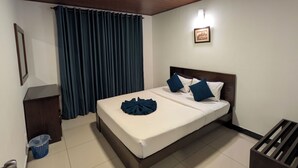 Una habitación de hotel con techo de madera, cama con ropa de cama blanca y almohadas azules, un cuadro enmarcado en la pared y una cortina azul.