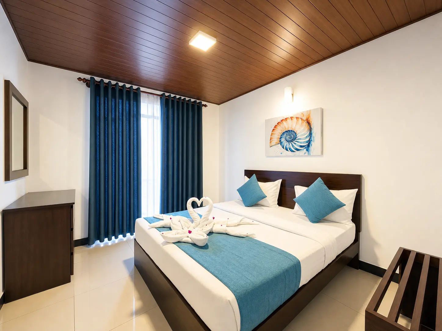 Habitación de hotel con cama, mesita de noche, una obra de arte en la pared y ventana con cortinas.