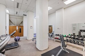 A gym with exercise equipment, a treadmill, and a mirror. - City Apt with Balcony and Parking by Zodiak Stays (Auckland)