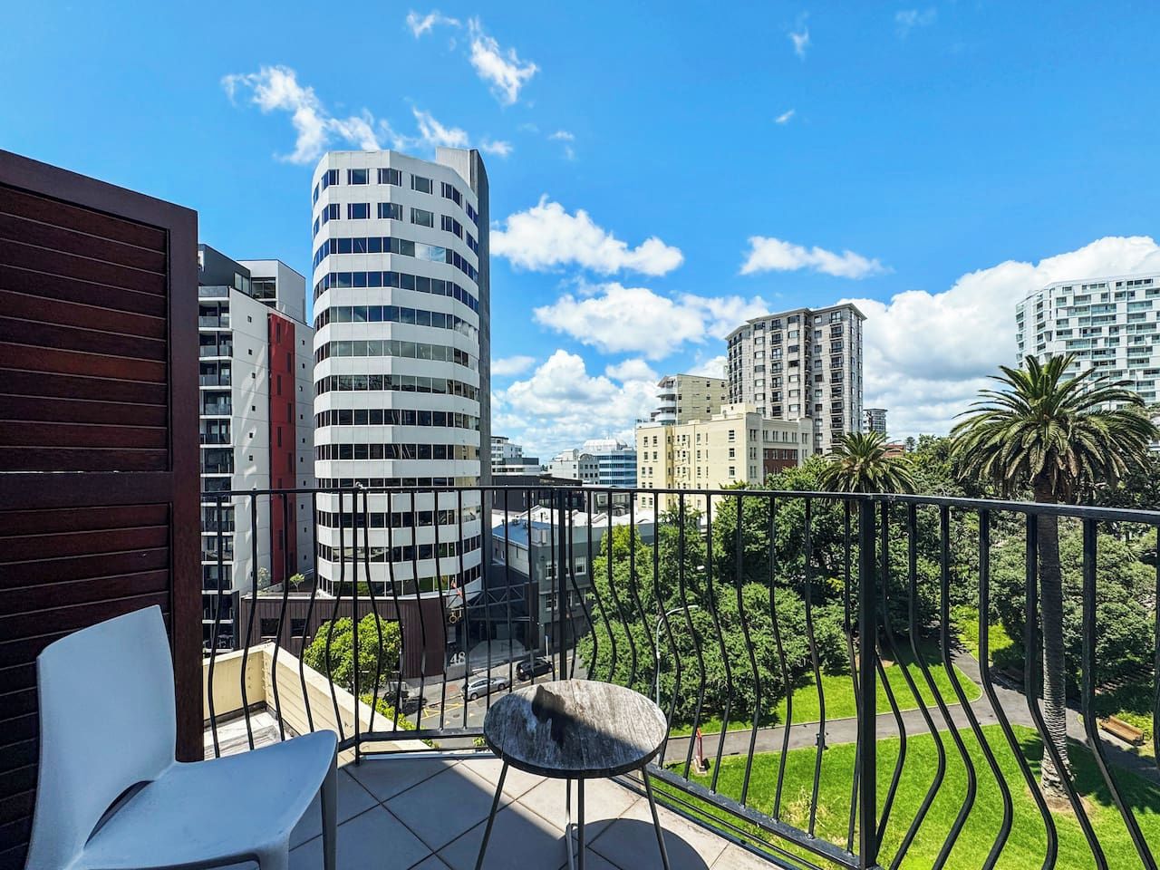 A balcony with a view of modern buildings, a chair, and a small table.
