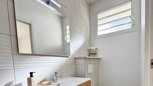 A modern bathroom with a wooden vanity, a white sink, a toilet, and a large mirror. - The cos cocoon, less than 10 minutes from the airport. (Ducos)