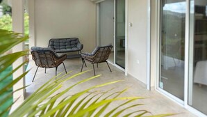 A modern patio with two chairs and a sofa, a glass door leading to a balcony, and a plant in the foreground. - The cos cocoon, less than 10 minutes from the airport. (Ducos)