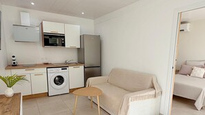 A compact living space with a kitchenette, a washing machine, a sofa, and a dining area. - The cos cocoon, less than 10 minutes from the airport. (Ducos)