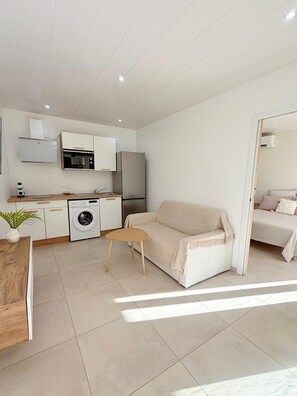 A compact living space with a kitchenette, a washing machine, a sofa, and a dining area. - The cos cocoon, less than 10 minutes from the airport. (Ducos)