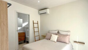 A bedroom with a bed, a wooden wardrobe, a ladder, an air conditioning unit, and a small bedside table. - The cos cocoon, less than 10 minutes from the airport. (Ducos)