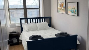 A bedroom with a bed, a window, and two framed pictures on the wall. - 2-bedroom Apartment in Central Brooklyn (Brooklyn)