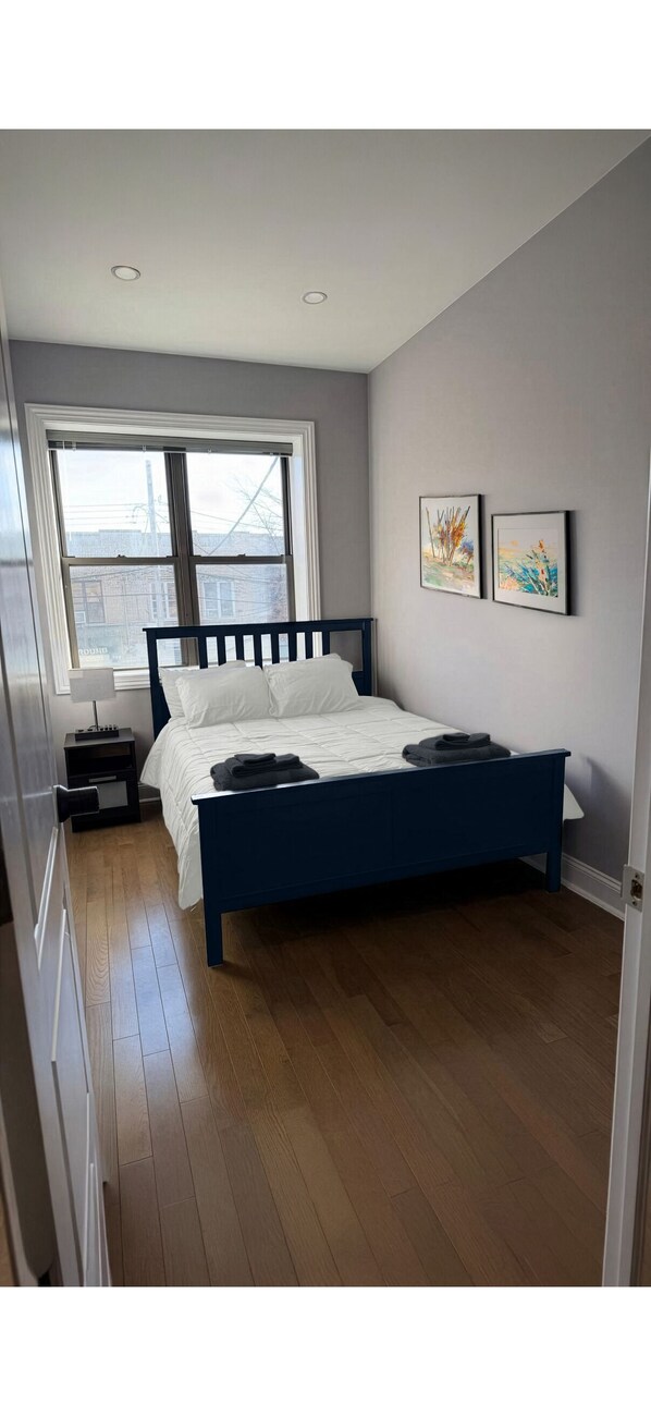 Une chambre à coucher avec un lit, une fenêtre et deux tableaux encadrés accrochés au mur.