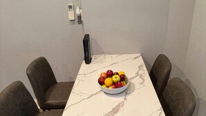 A dining table with a marble top, surrounded by four grey chairs, a bowl of fruit, and a framed picture on the wall. - 2-bedroom Apartment in Central Brooklyn (Brooklyn)
