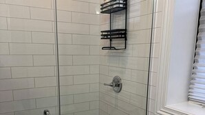 A glass-enclosed shower with white tiled walls and a black and white patterned floor. - 2-bedroom Apartment in Central Brooklyn (Brooklyn)