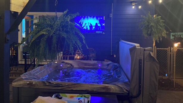 Ein Whirlpool mit Fernseher im Hintergrund, umgeben von Pflanzen.