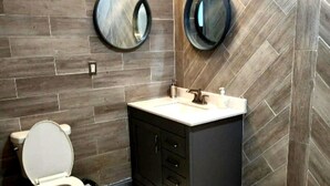 A bathroom with a toilet, vanity, and two round mirrors.