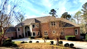 A two-story house with a front entrance, a driveway, and a well-maintained lawn.