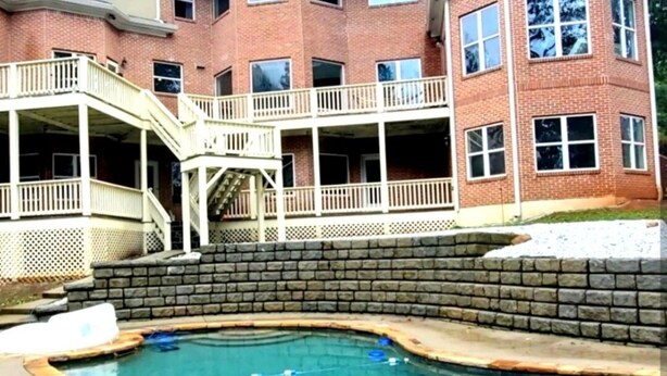 A two-story house with a swimming pool, a covered patio, and a brick exterior.