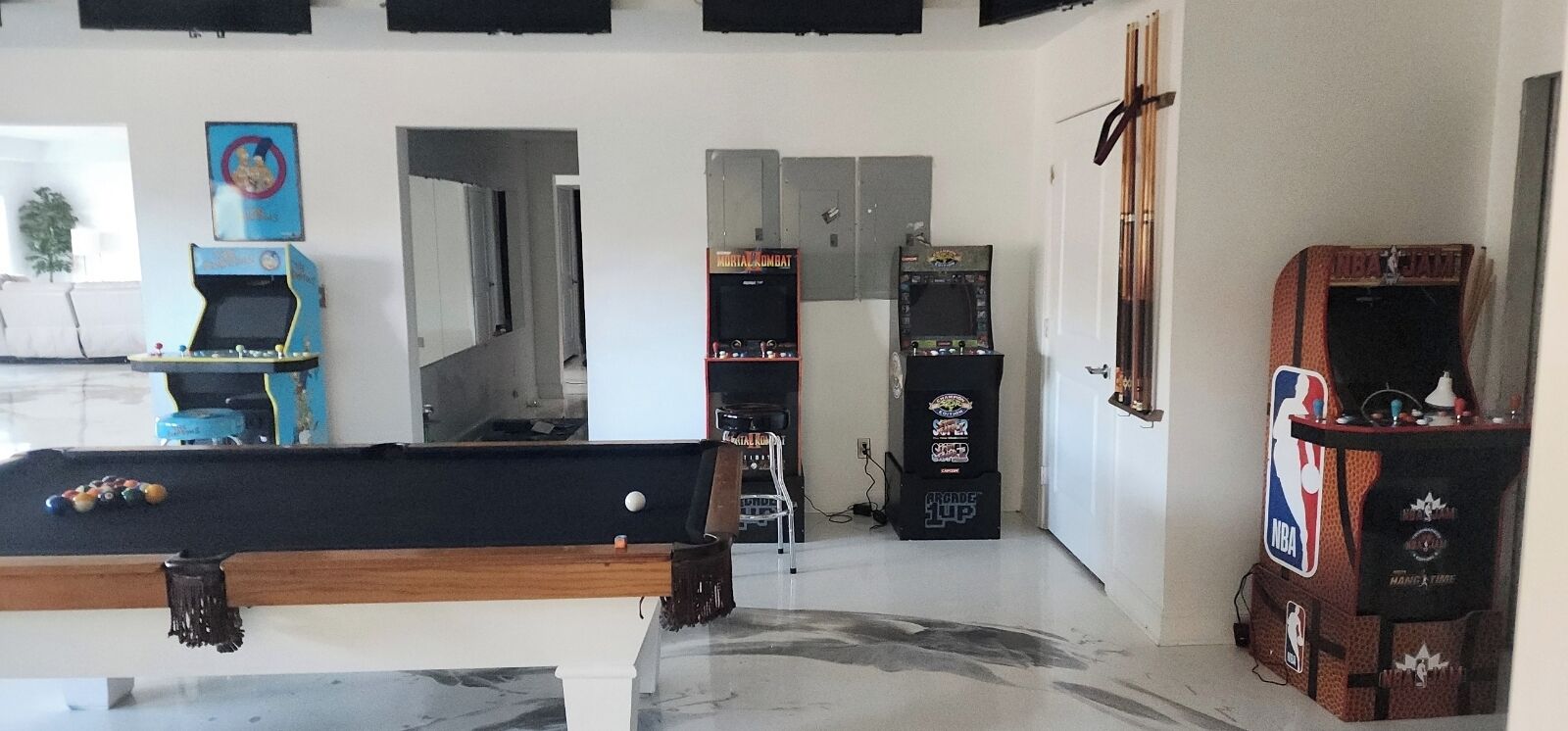 Una stanza con tavolo da biliardo, giochi arcade e una porta che conduce in un'altra stanza.