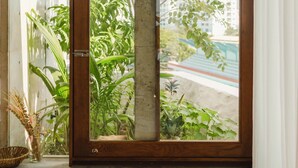 A window with a view of greenery and a building in the background. - The Still (Nam Nha Trang)