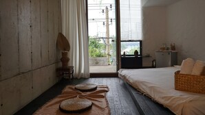A room with a bed, a small table, a lamp, and a view through a door. - The Still (Nam Nha Trang)