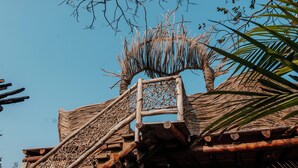 A wooden structure with a woven roof, a ladder, and a palm tree.