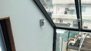 Un appartement situé dans un immeuble de grande hauteur, doté d’une grande fenêtre, d’une rambarde en métal et offrant une vue sur le paysage urbain.