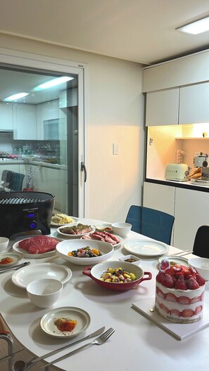 A dining table with various dishes, a toaster, and a refrigerator in the background. - 해변가가 가깝다! K-바베큐가 가능한 4층 건물, 복층 스테이 (Ulsan)