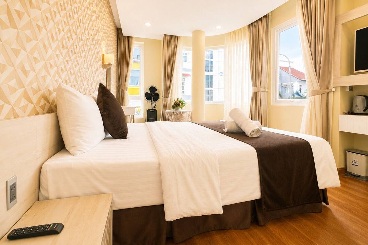 A hotel room with a bed, a desk, a TV, and a window with curtains.