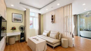 A modern living room with a sofa, a small table, a fan, and a picture on the wall. - Silentnight - Đêm Lành Hotel (Xuan Huong - Da Lat)