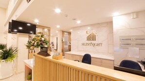 A reception desk with a 'Silent Night' sign, a television, and a potted plant. - Silentnight - Đêm Lành Hotel (Xuan Huong - Da Lat)