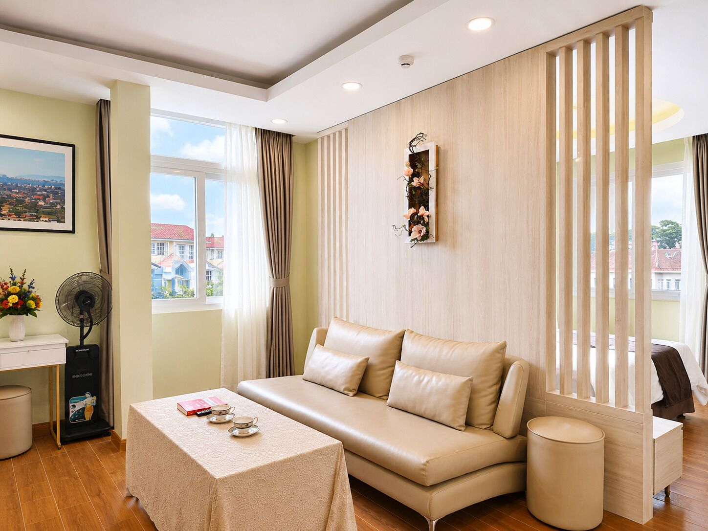 Een moderne hotelkamer met een bank, een tafeltje, een ventilator en uitzicht op de stad.