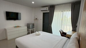 A modern hotel room with a large bed, a flat-screen TV, a dresser, and a desk with a chair. - I Am Daily Mansion (Pluak Daeng)