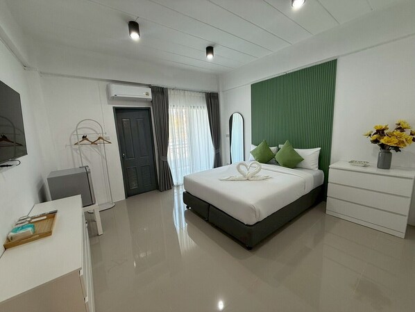 A modern hotel room with a bed, bedside table, dresser, and a TV. - I Am Daily Mansion (Pluak Daeng)