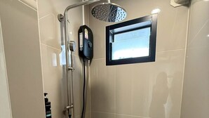 A small, tiled shower room with a handheld showerhead, a wall-mounted showerhead, and a window. - I Am Daily Mansion (Pluak Daeng)