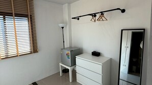 A modern room with a white wardrobe, a small table with a lamp, a refrigerator, and a mirror. - I Am Daily Mansion (Pluak Daeng)