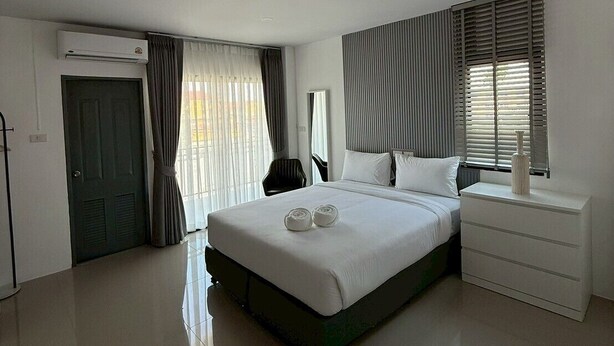 A modern hotel room with a large bed, a bedside table, a wardrobe, and an air conditioning unit. - I Am Daily Mansion (Pluak Daeng)