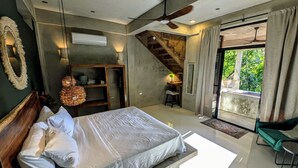 Un dormitorio con una cama, un escritorio, una silla, una escalera y vistas a zonas verdes.