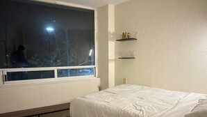 A bedroom with a bed, a window, a shelf, and a ceiling light. - Encantador depa en Polanco, Ideal para viajeros. (Ciudad de México)