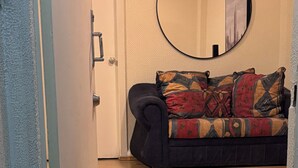 A hallway leading to a room with a patterned sofa, a round mirror on the wall, and a welcome mat with 'BEN VENIDO' text. - Encantador depa en Polanco, Ideal para viajeros. (Ciudad de México)