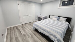 A bedroom with a bed, a nightstand, a wardrobe, and a window. - Newly renovated 2 bedroom basement with seperate entrance. (Whitby)