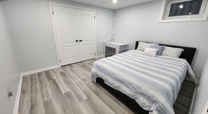 Un dormitorio con una cama, una mesita de noche, un armario y una ventana.