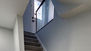 A staircase with wooden steps and white walls, leading to a room with a window. - Newly renovated 2 bedroom basement with seperate entrance. (Whitby)