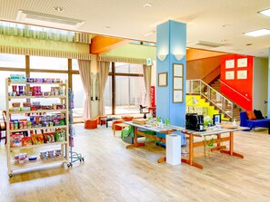 A spacious room with a large window, a staircase, and a variety of items on shelves and tables. - Chiisana Hotel SHIMOKOSHIKI (Satsumasendai)