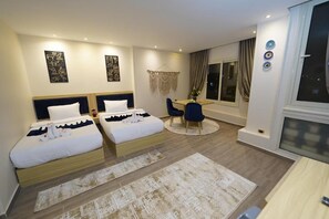 A hotel room with two beds, a dining table, chairs, a large window, and decorative wall art. - Pyramids Khan Hotel (Giza)