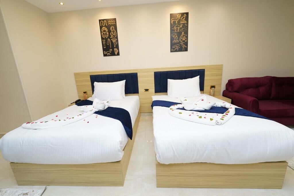 Two twin beds with white linens and blue headboards in a hotel room.