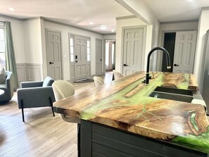Une cuisine moderne dotée d’un îlot central, d’un robinet noir et offrant une vue sur un coin repas avec des chaises et une table.