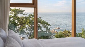 A bedroom with a large window overlooking a coastal view. - Pohang Sausalito by B-class Pool Villa (Pohang)