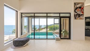 A modern room with a large sliding glass door leading to a pool, a comfortable seating area, and a view of the sea. - Pohang Sausalito by B-class Pool Villa (Pohang)