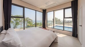 A bedroom with a large bed, a view of the sea, and a swimming pool. - Pohang Sausalito by B-class Pool Villa (Pohang)