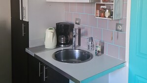 Eine kleine Küche mit Spüle, Schränken und einer Kaffeemaschine.