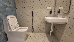 Une salle de bain avec des toilettes, un lavabo et une douche.