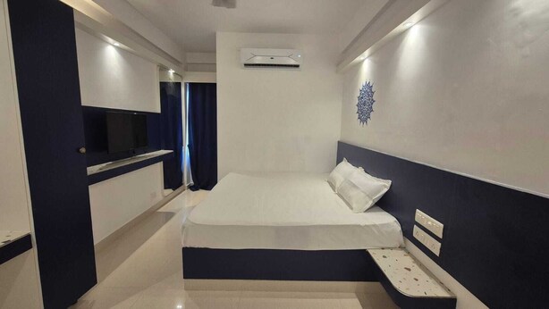 Une chambre d’hôtel équipée d’un lit, d’une télévision, d’une petite table et d’un appareil de climatisation.