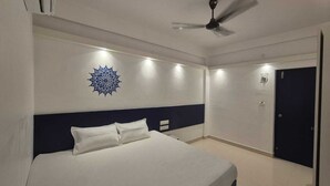 Une chambre à coucher comprenant un lit, un ventilateur de plafond, un élément décoratif mural et une porte.